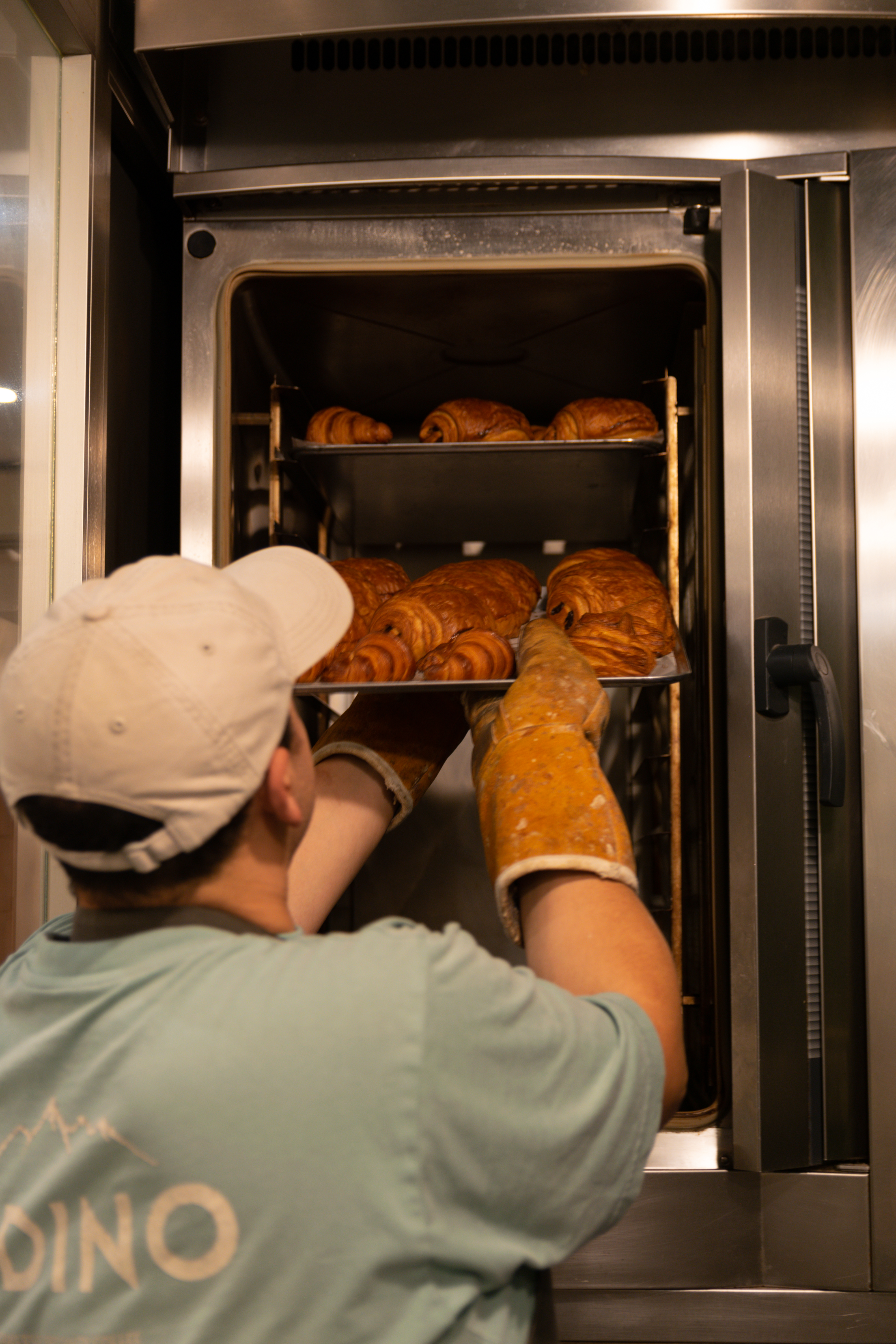 Panadero sacando una bandeja de croissants del horno en ObradorAndino